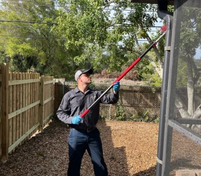 Joe Potter clearing spider webs and pests from gutters at a residential property